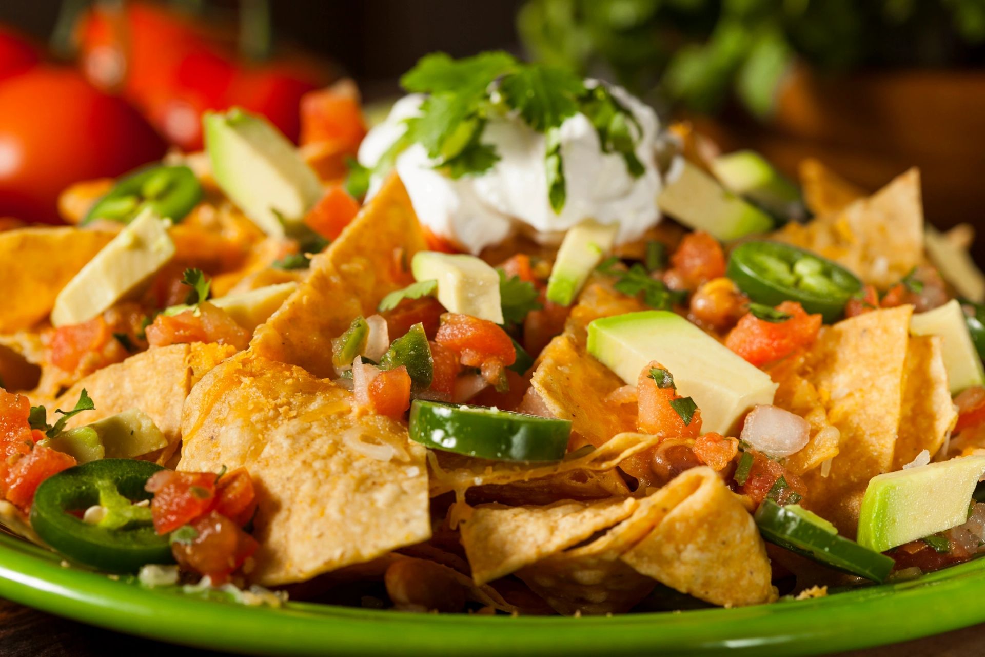 Nachos topped with fresh tomato, avocado, cilantro and sour cream